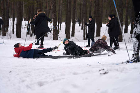Russia, Naberezhnye Chelny, February 13, 2020: teenagers go skiing. A few teenagers have fallen in the snow, they are laughing. Selective focus.のeditorial素材