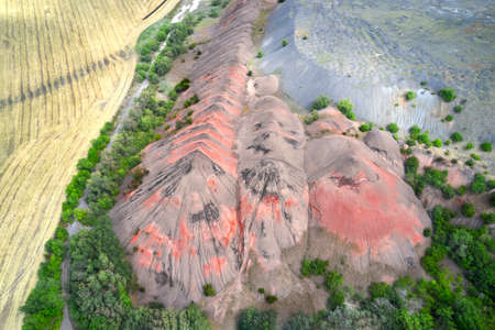 Anthropogenic terrain. The border of the wheat field runs along a cascade of waste piles formed as a result of coal mining. Shooting from a drone.の写真素材