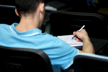 Business training. A young man takes notes on a lecture in a notebook. Selective focus.