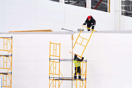 Russia, Naberezhnye Chelny, March 5, 2021: workers collect scaffolding on the facade of the building.のeditorial素材