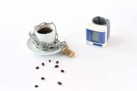 Coffee under lock and key. Next to the coffee cup, wrapped in a chain, is a blood pressure monitor....