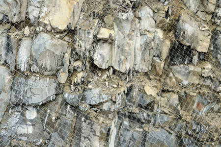 Anti-avalanche measures in mountainous areas. The steep rocky slope along the road is covered with metal mesh. Copy space.の写真素材