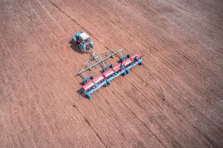 Spring field work. Sowing seeds in the soil with a tractor. Shooting from a drone. Copy space.