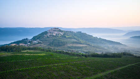 An ancient fortress town on a mountain in the middle of an agricultural landscape in the early morning. Shooting from a drone.の写真素材