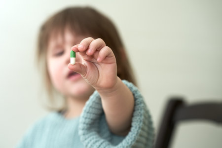 A medicine capsule in a child's outstretched hand. The image of the child is blurred. Selective focus. Copy space.の写真素材