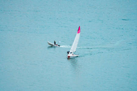 Sailing training on the lake. A motorboat is speeding around a sailing yacht. Copy space.