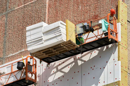 Insulation of a multi-storey building from the outside. Two construction bassinets with facade...