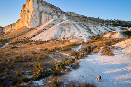 Aerial view of a white rocky mountain with motorcyclists entering a steep slope. Shooting from a...