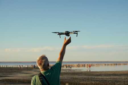 A man takes a drone at arm's length on the shore of the lake. Selective focus. Copy space.