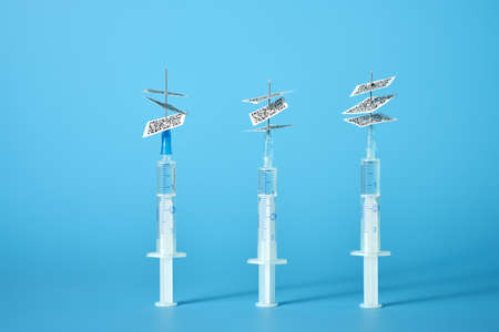 Syringes with QR codes impaled on a needle on a light blue background. Copy space.