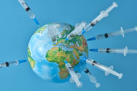 A globe studded with a lot of syringes with a vaccine on a light blue background close-up. Concept. Copy space.の写真素材
