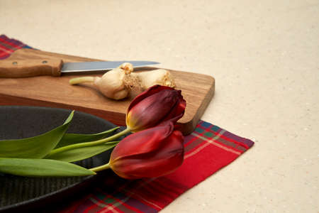 Tulip cooking. Dark red tulip flowers on a plate next to tulip bulbs on a cutting board. selective focus.の写真素材