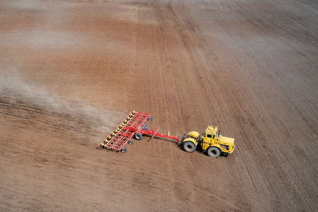 The tractor processes the field with a combined arrow. Shooting from a drone.