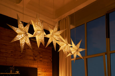 An element of the Christmas decor of a wooden dwelling suspended from the ceiling with glowing...