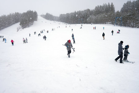Russia, Fedotovo, January 2, 2022: ski resort. A ski track with a lot of skiers and snowboarders. snowfall.のeditorial素材