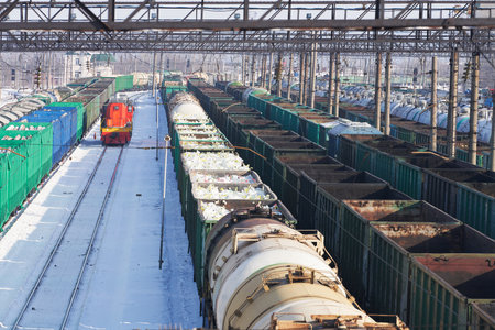 Cargo transport by rail. Railway station with many freight trains with a variety of cargo. Winter.