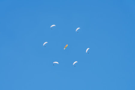 A group of paragliders in the shape of a circle (flower) in the air on the blue sky background. Copy space.の写真素材