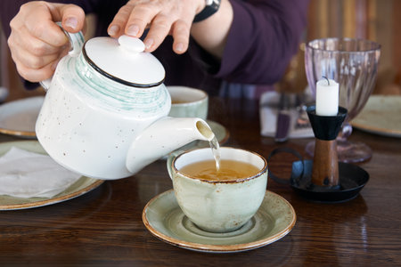 Woman's hands pouring green tea from teapot into cup.の写真素材