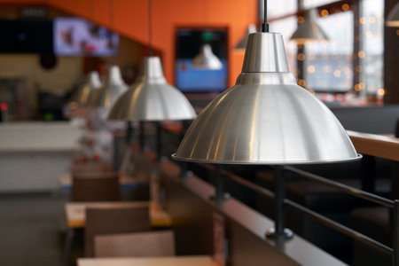 Fragment of restaurant interior with metal hanging lampshades over tables as background image. Copy space.の写真素材