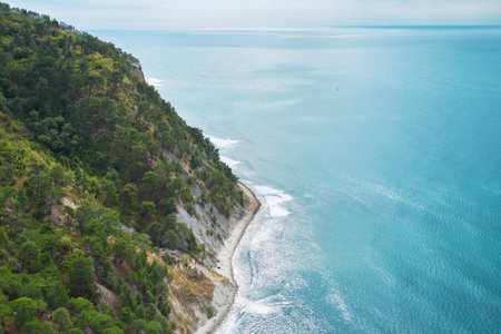 Panoramic aerial view of the picturesque wild beach "Blue Abyss" stretching in a narrow strip at the foot of a forested mountain. The descent to the sea is steep through a pine forest.の写真素材