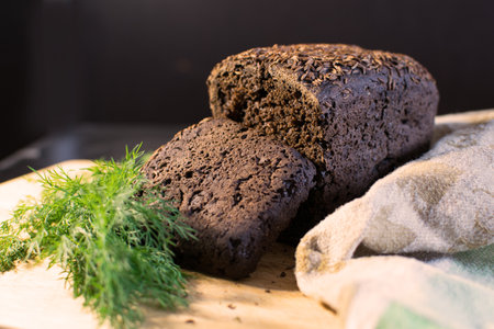 Black bread with dill and parsley on a cutting board.
