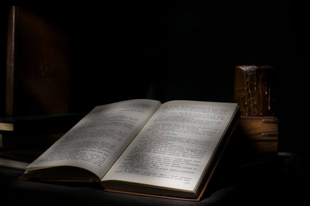 Old books on a black background with a candle in the dark.
