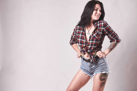 Tattooed brunette in plaid shirt on gray backgroundの写真素材