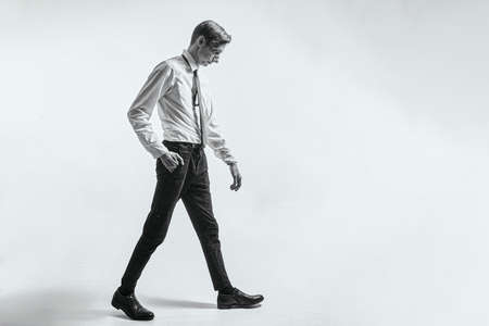 Tired man - a worker is walking on a gray background