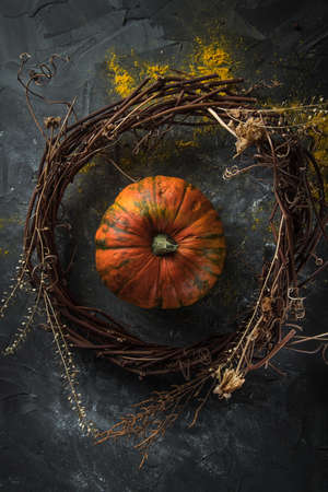 beautiful pumpkin inside a decorated wreath of twigs and dry herbs on a dark stone table. Top viewの写真素材