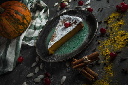 beautiful piece of pumpkin pie with cranberries and powdered sugar on a stone table. Nearby are pumpkin and cinnamon sticks. Top viewの写真素材