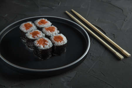 classic sushi with salmon on a beautiful plate, on a stone black table. Nearby are Chinese sticks. Top Side viewの写真素材