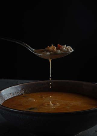 spoon with tom yam soup on the background of a plate on a stone table. Side viewの写真素材