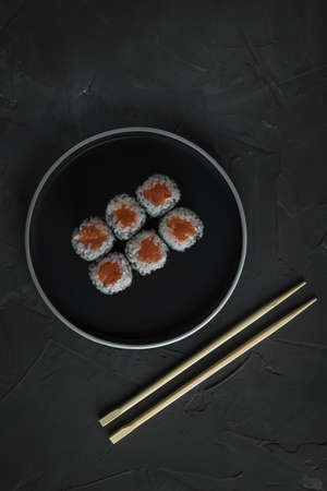 classic sushi with salmon on a beautiful plate, on a stone black table. Nearby are Chinese sticks. Top viewの写真素材