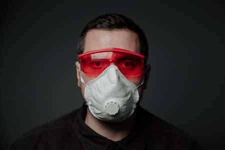 young white male in construction respirator and glasses on dark backgroundの写真素材