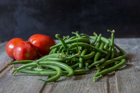 Green beans with cherry tomatoes on wooden background