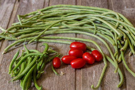 Green beans with cherry tomatoes on wooden backgroundの写真素材