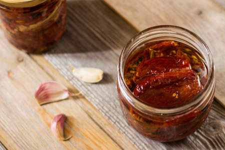 Dried tomatoes in a jar with extra virgin olive oil, oregano and garlic. Selective focusの写真素材