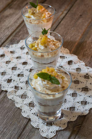 Mango mousse in glass cup with mint on wooden backgroundの写真素材