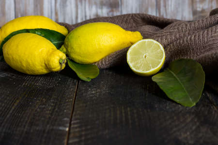 Lemons and leaves on black wooden backgroundの写真素材