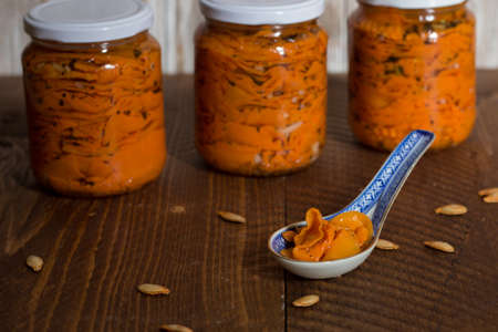 Sweet and sour pumpkin in glass jar on old wooden background, selective focus.の写真素材
