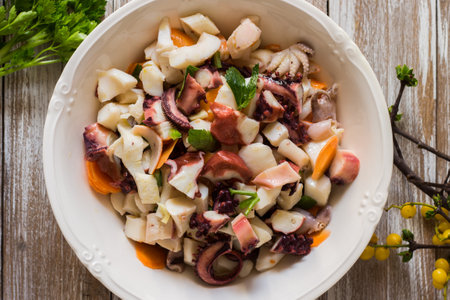 Seafood salad dressed and served in porcelain bowl on wooden backgroundの写真素材