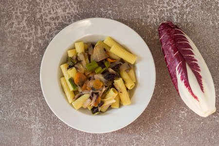 Rigatoni with radicchio served in a white plate on a gray background. Italian pasta with vegetables. Vegan recipe.の写真素材