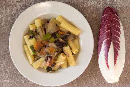 Rigatoni with radicchio served in a white plate on a gray background. Italian pasta with vegetables. Vegan recipe.の写真素材
