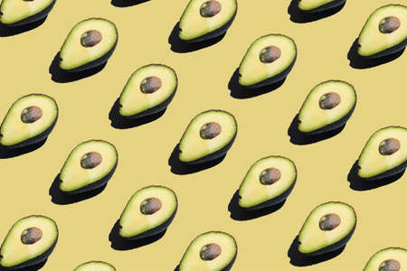 A hard light pattern of a half of an avocado with seed on pale green backgroundの写真素材