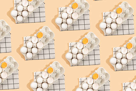 A top view of a set of eggs in an egg form, including several cracked and an egg yolk, on a kitchen towel, hard light patternの写真素材