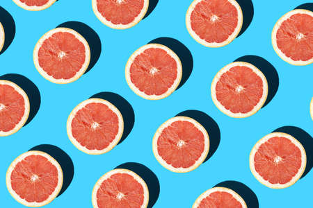 A hard light pattern of an grapefruit half on a blue surfaceの写真素材
