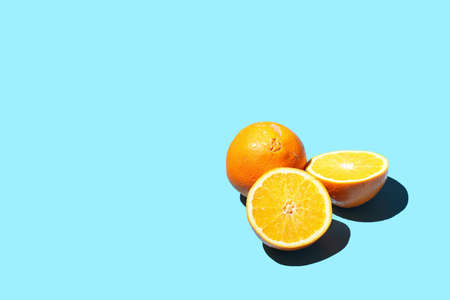 A half of an orange with hard light shadow on a blue surface, two pieces and a whole orange, a templateの写真素材