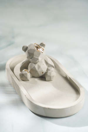 A gray concrete figurine of a teddy bear on a concrete tray on pastel blue backgroundの写真素材