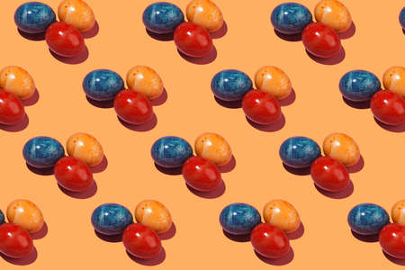 A hard light pattern of three colored easter eggs on an orange backgroundの写真素材