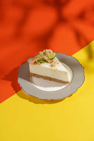A piece of a lime cheesecake on a romantic plate on a bright orange-yellow surfaceの写真素材